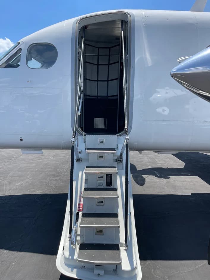 A close-up view of the open main entry door and integrated stairs of a white aircraft.
