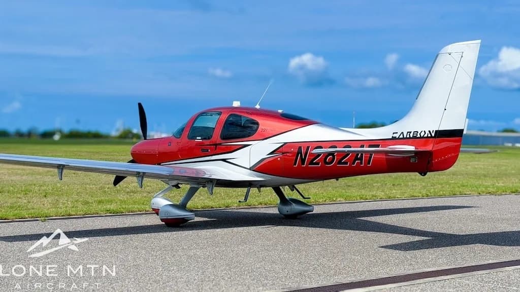 A red and silver Cirrus SR22T aircraft, registration N282AT, parked on an tarmac with a distant blue horizon.