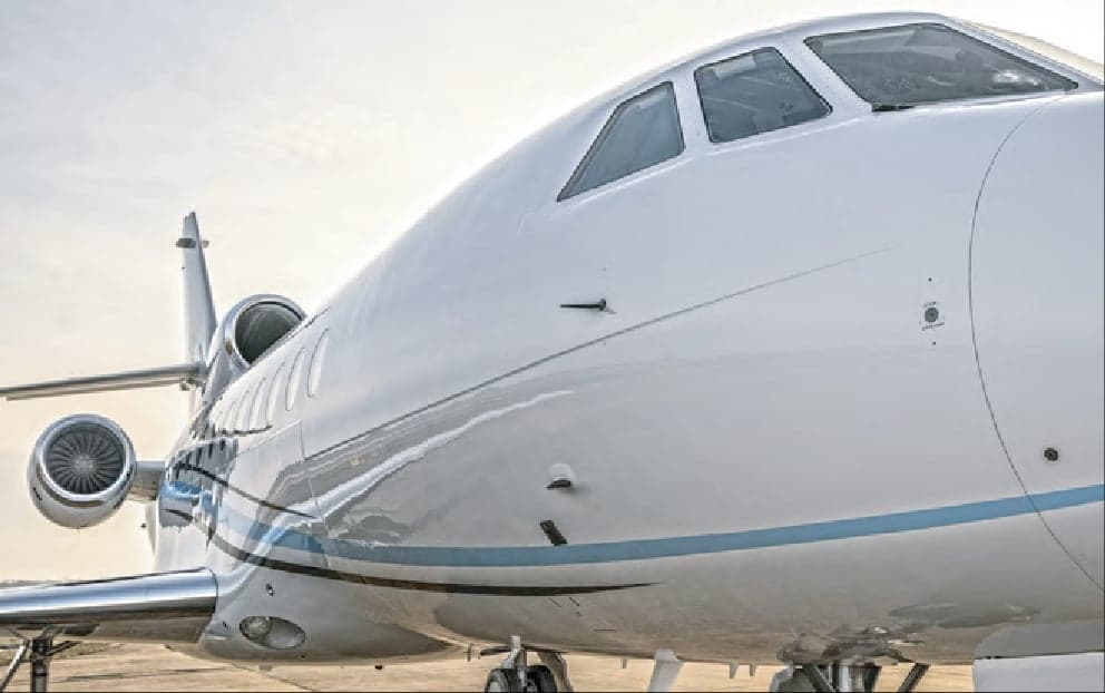 Close up of the nose and cockpit of a white Falcon jet.