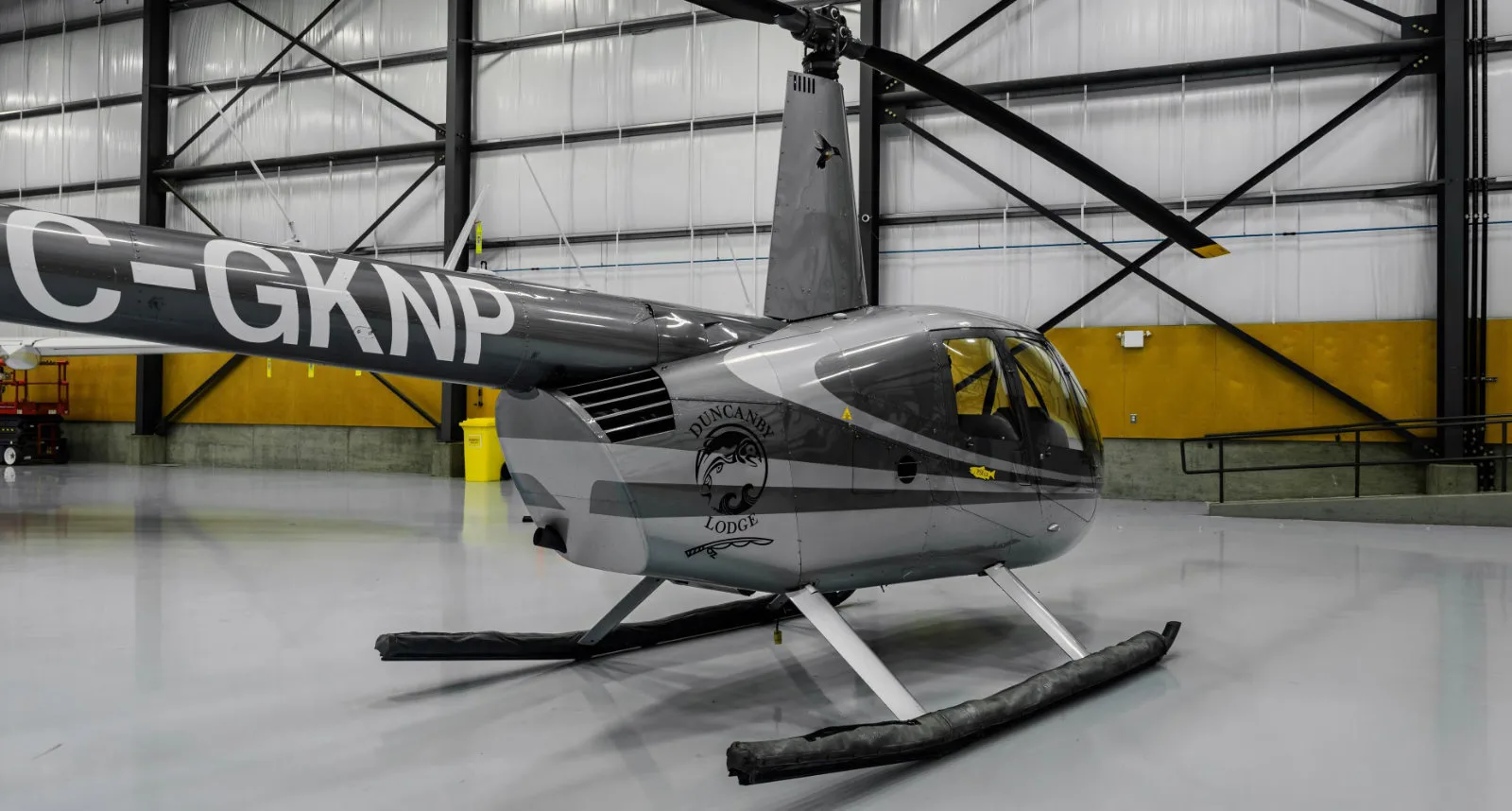 Robinson helicopter C-GKNP with Duncansby Lodge logo inside a hangar.