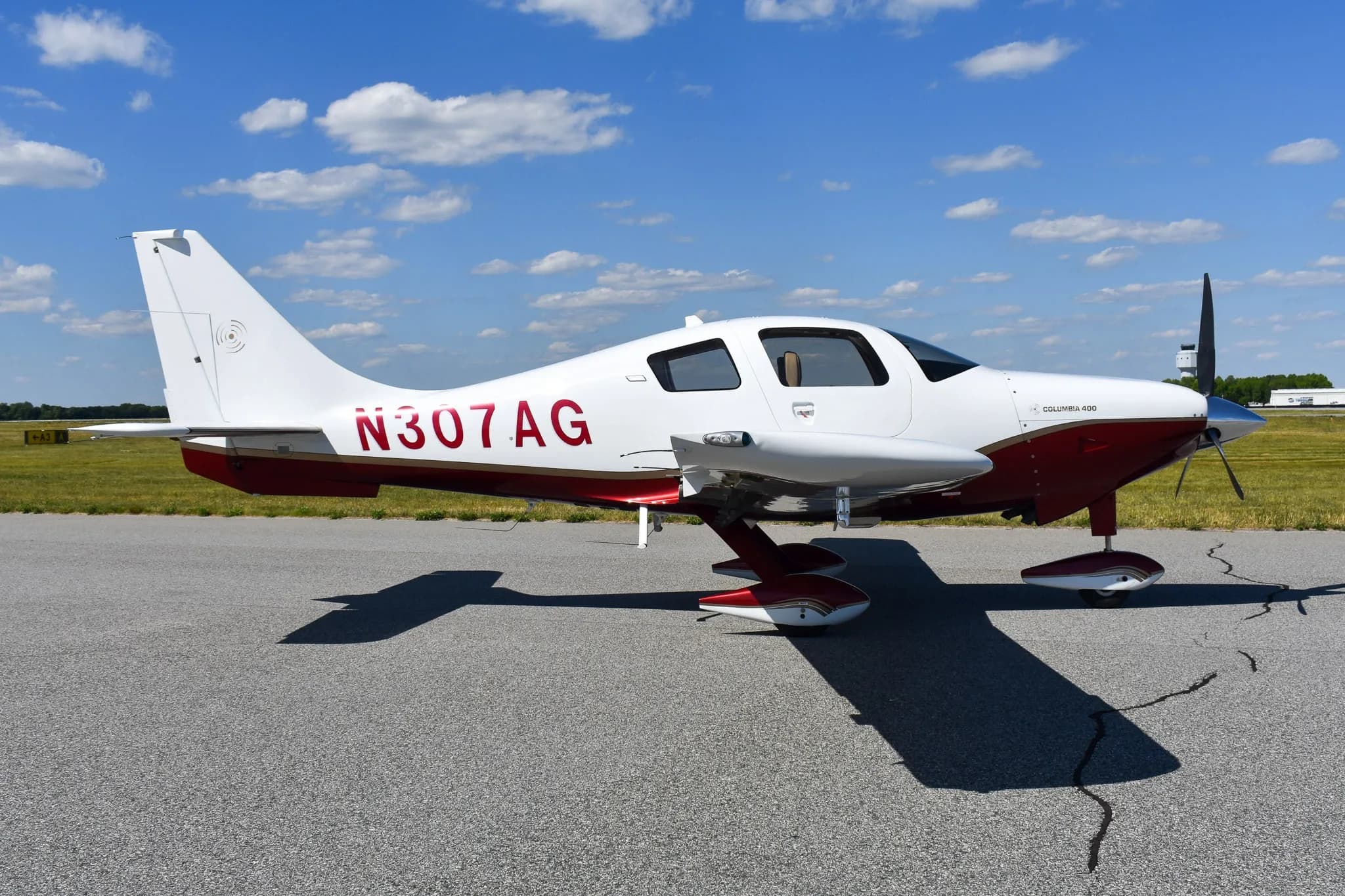 Side profile of a white and maroon Columbia 400 aircraft with registration N307AG on an airfield.