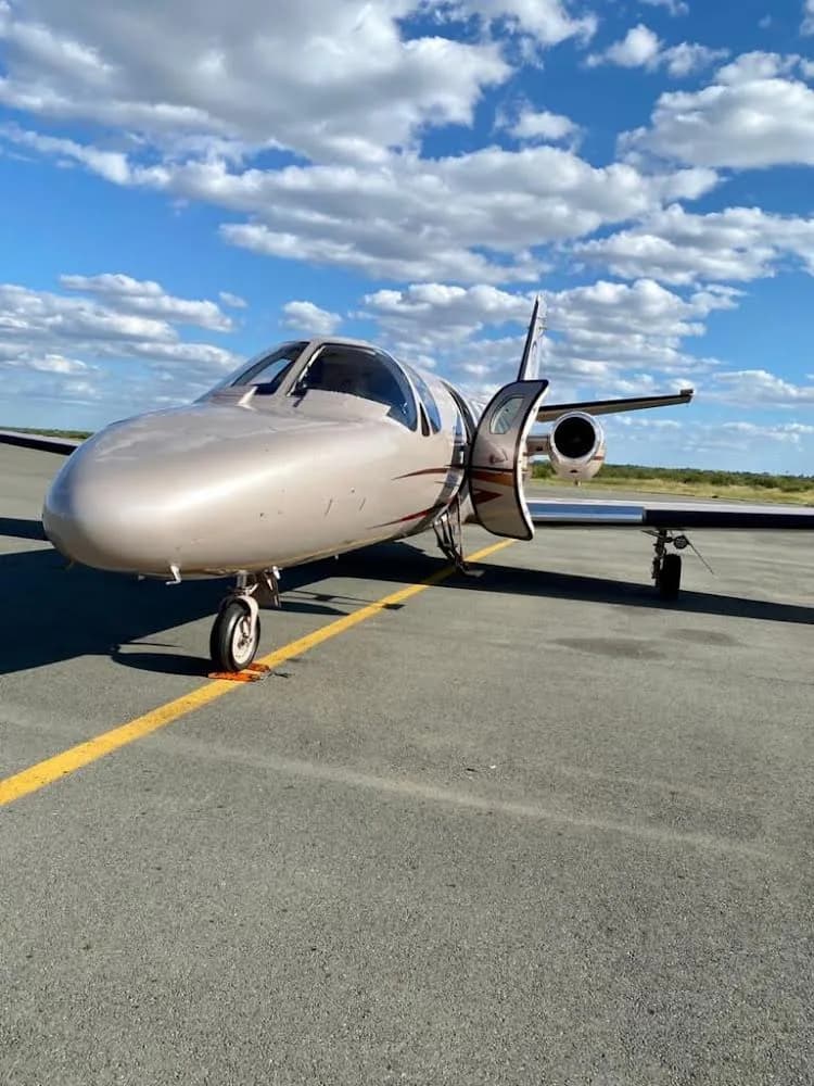 Side view of A2-PGC Cessna Citation Mustang on the tarmac with the door open.