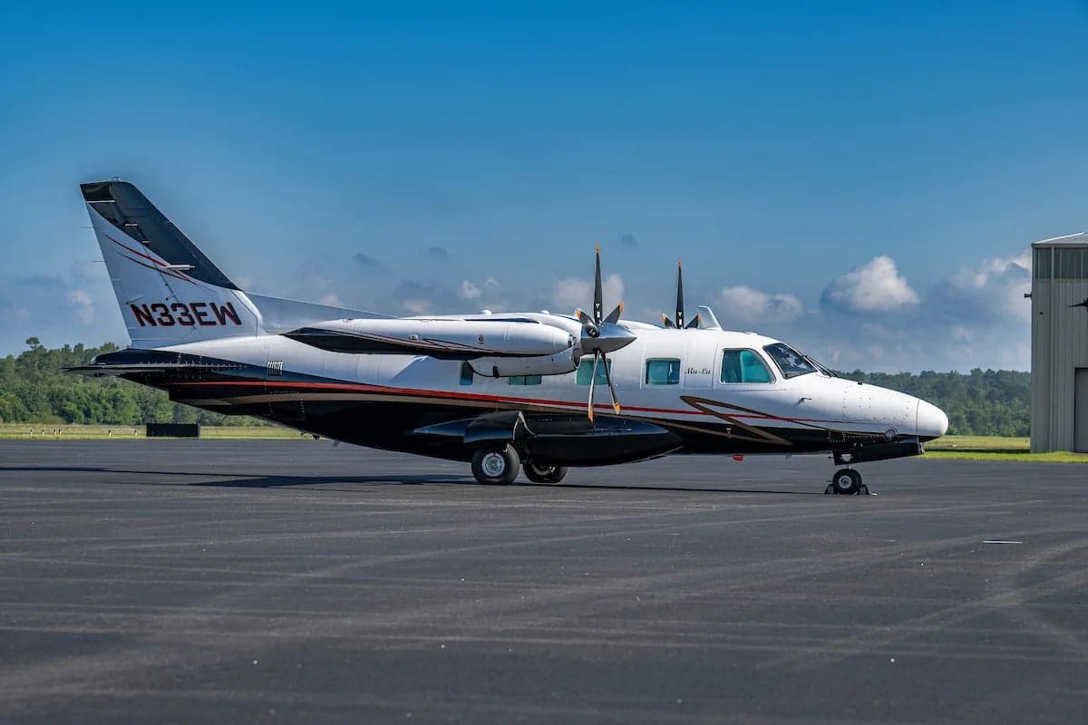 Side view of the N33EW aircraft on the tarmac with a black, white, and gold paint scheme.