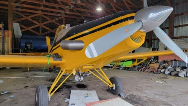 A yellow and black Air Tractor AT-400 sits inside a hangar.