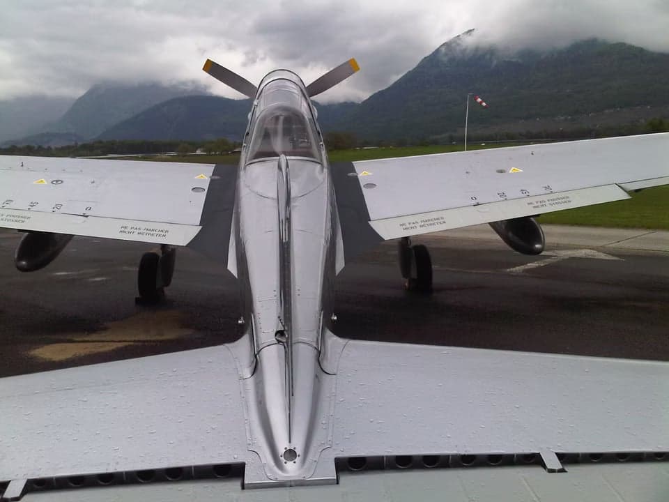 Wing and fuselage of a P-3 Pilatus with Swiss markings and Abode Globe logo.