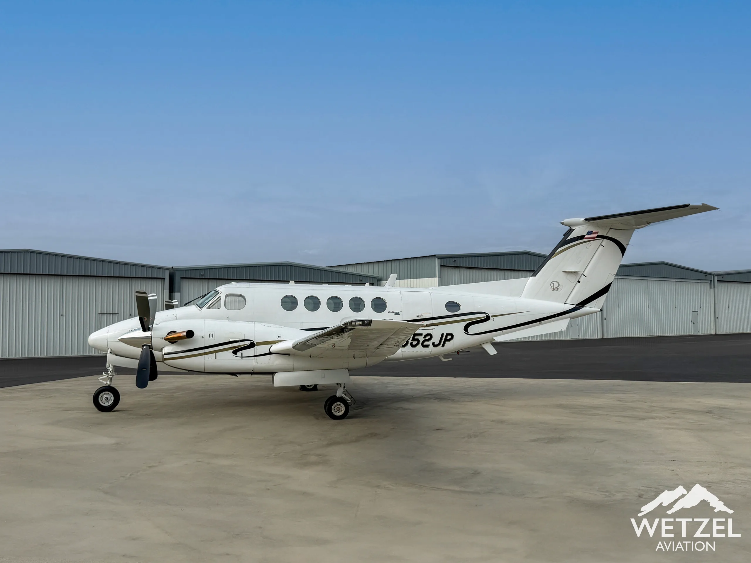 King Air 350 with registration N352JP parked in front of a hangar.
