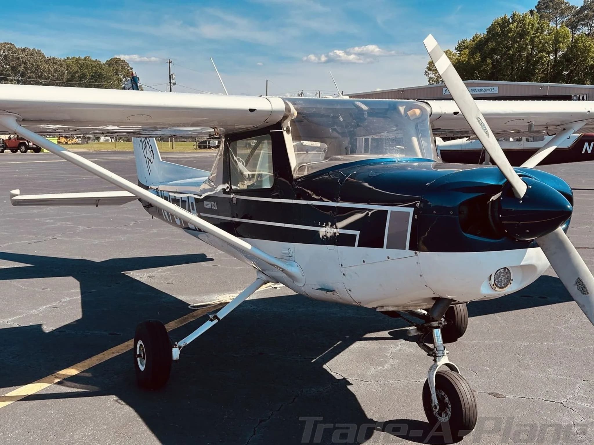 Front-right view of a white and blue Cessna 152 (N757ZR) parked on an asphalt ramp.