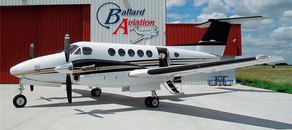 King Air aircraft parked outside a hangar with the door open.