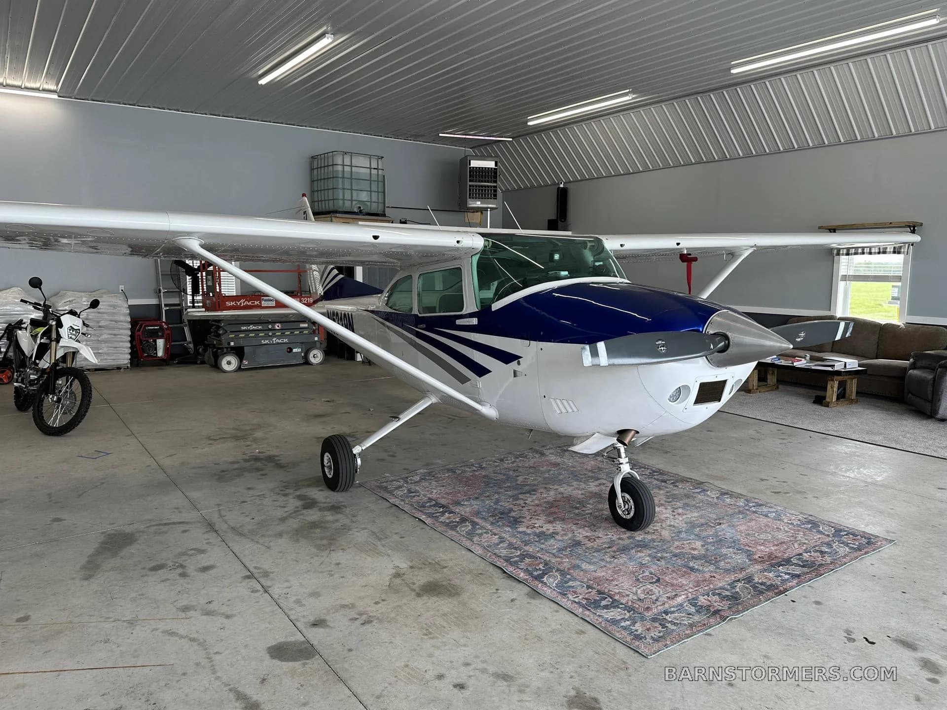 A white and blue Cessna aircraft with registration N5319N is parked head-on inside a hangar.