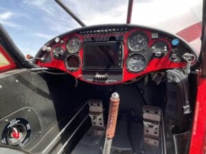 The cockpit of the red aircraft features a modern instrument panel.