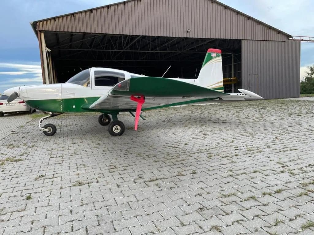 Side view of N90704 aircraft parked in front of a hangar.