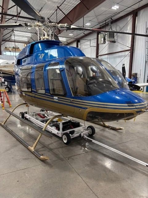 A blue and gold helicopter is shown in a hangar.