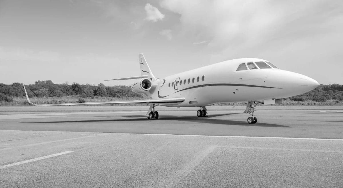 A Falcon aircraft is parked on the tarmac in black and white.