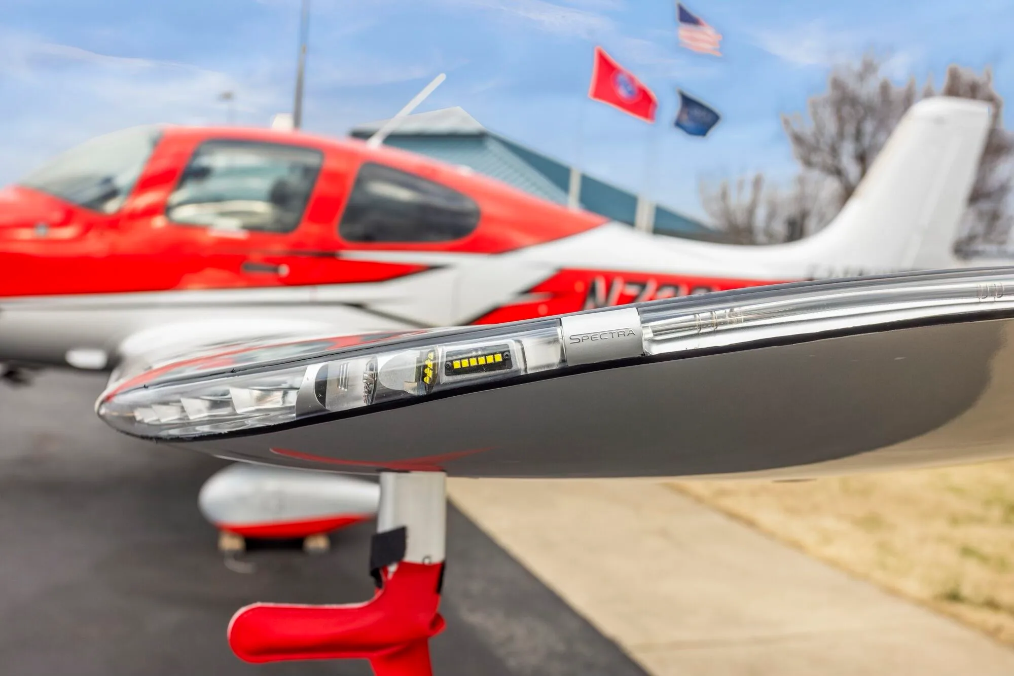 A close-up view of the wingtip light assembly on a red and silver Cirrus SR22 aircraft.