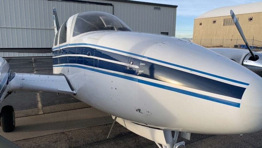 Close up of the nose of a Beechcraft Baron with a white and blue paint scheme.