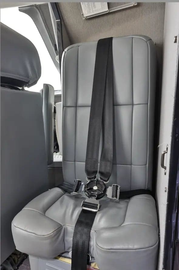 A gray seat with a seatbelt inside the aircraft cabin.