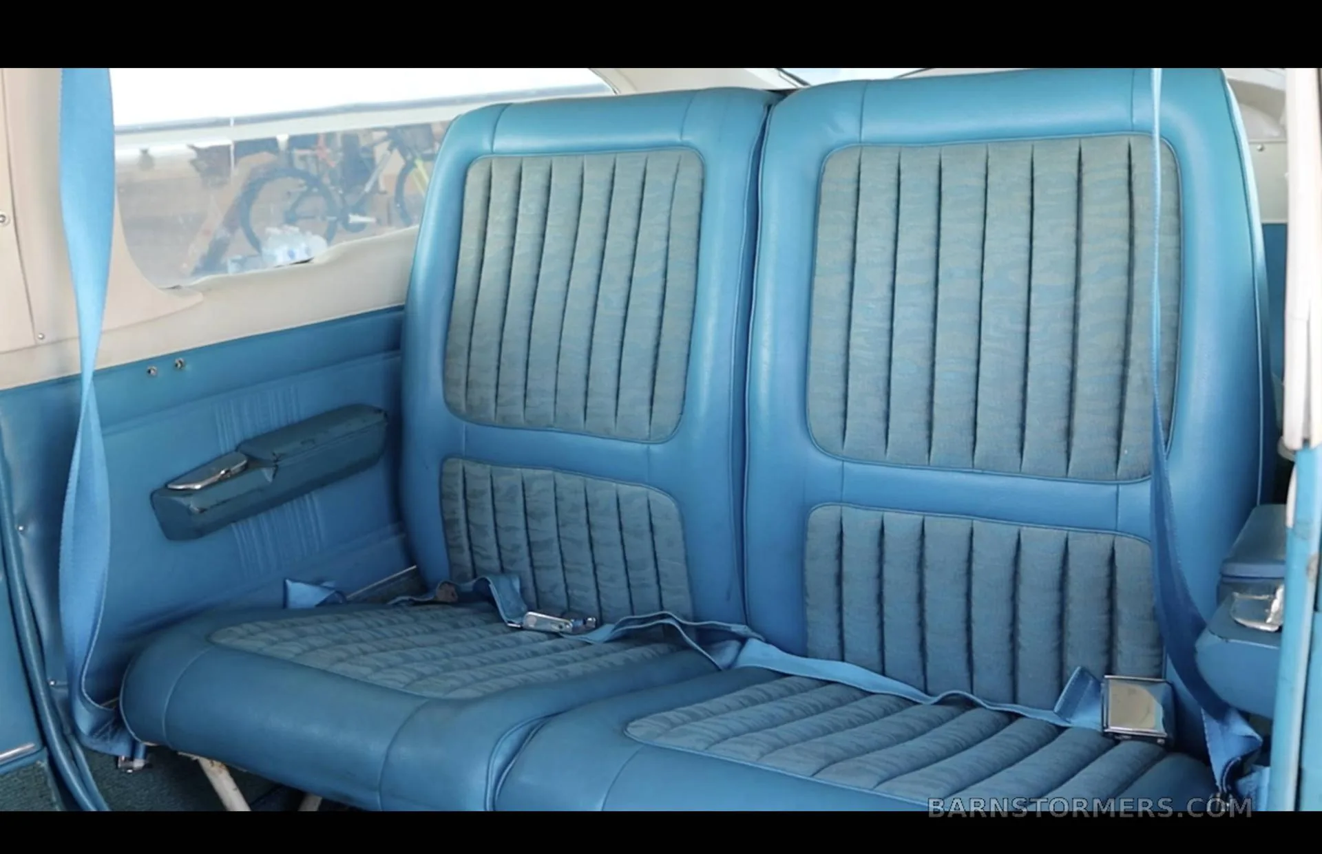 The rear blue upholstered seats of a Cessna 210 Centurion cabin.