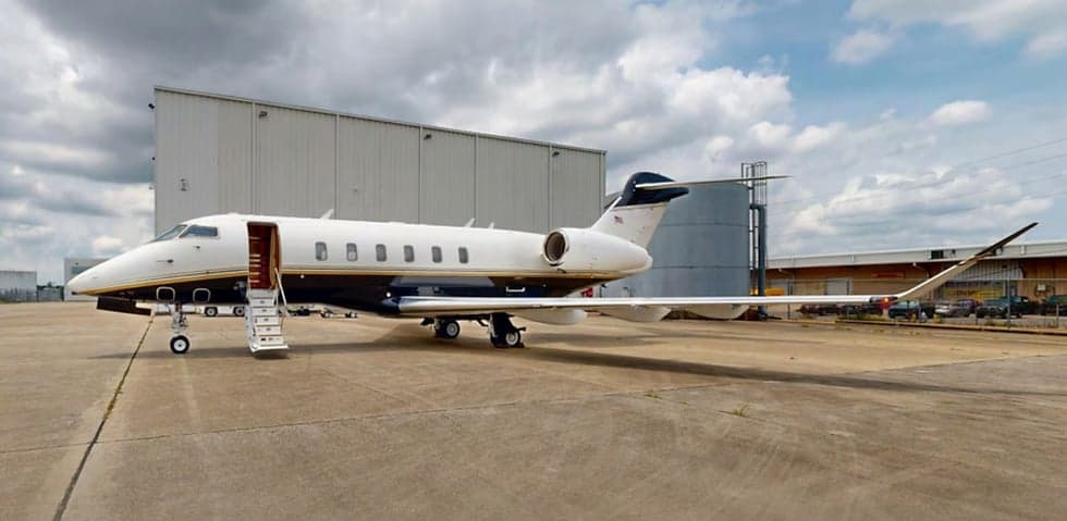 A Challenger aircraft is parked on the tarmac with the entry stairs down.