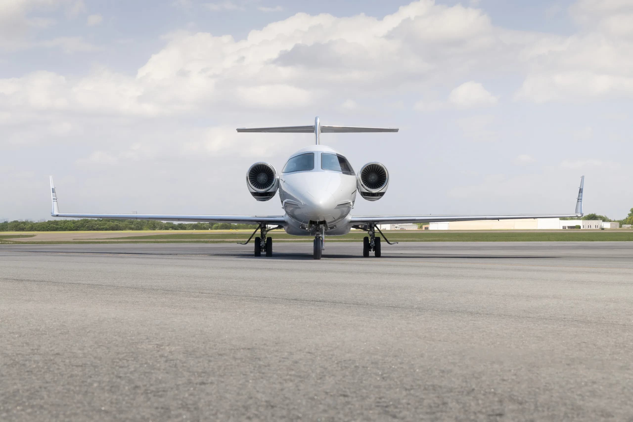 A white Learjet 60, registered N645FD, viewed head-on, parked on an asphalt runway under a partly cloudy sky.