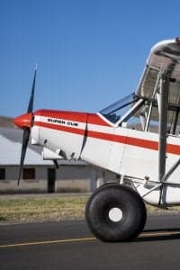 Close-up of the front of a Piper Super Cub aircraft with a red and white paint scheme.