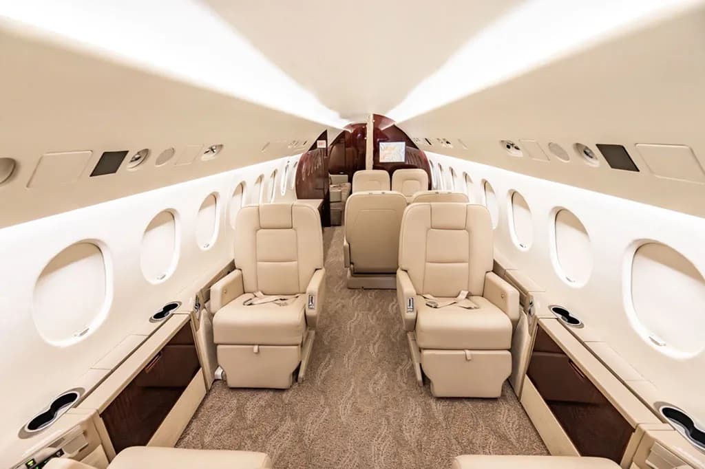 The luxurious interior cabin of the business jet, featuring beige leather seats and a brown and white color scheme.