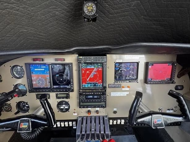 The cockpit of an aircraft featuring multiple modern glass displays, traditional gauges, and control yokes.