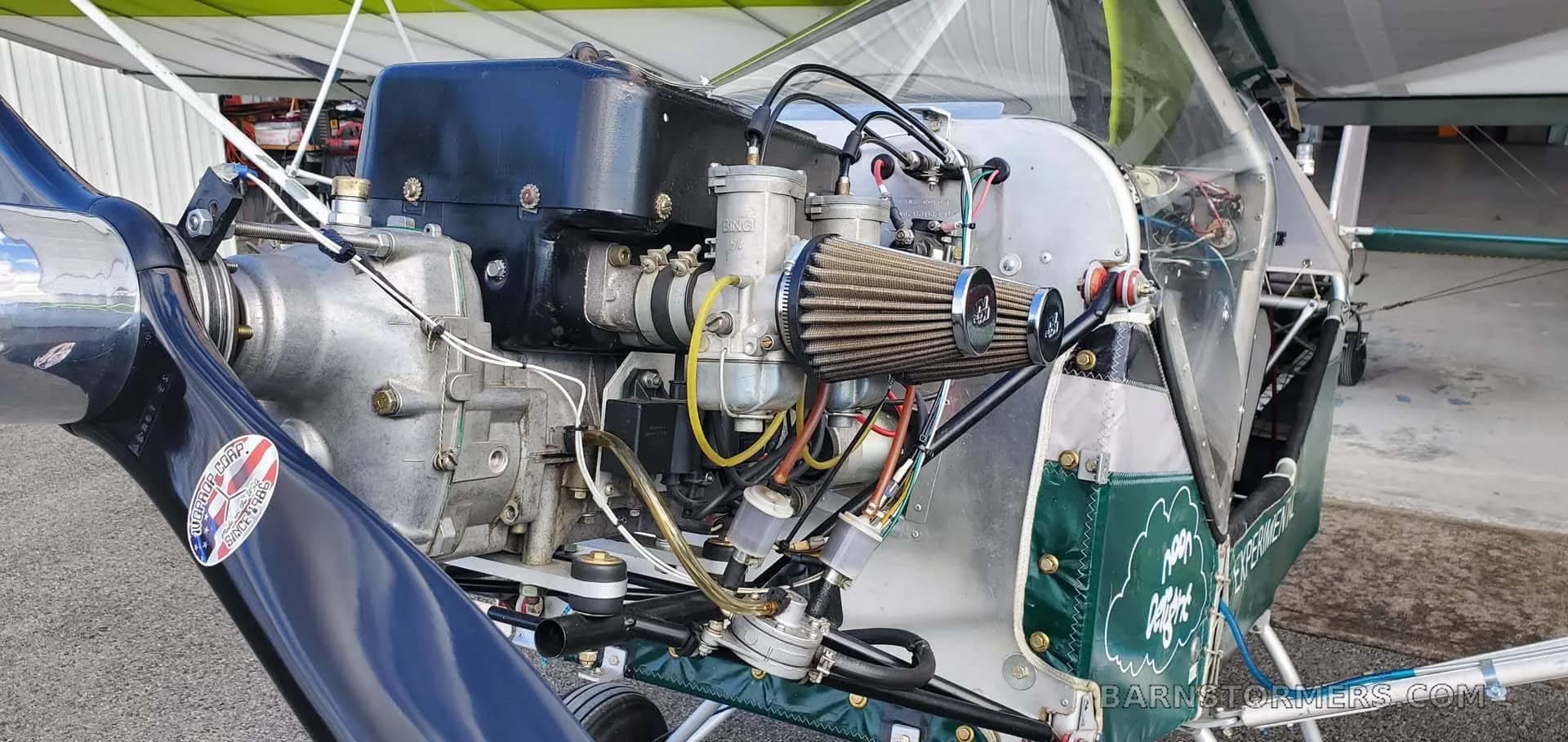 A detailed close-up of the aircraft's engine, propeller, and carburetor assembly.