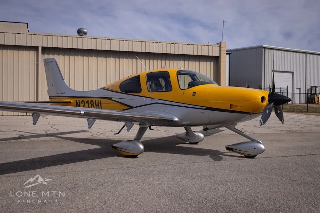 A Cirrus SR22 aircraft with yellow and silver paint scheme parked on an airfield.