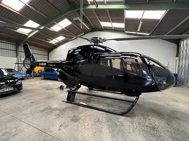 G-IZOB helicopter in a hangar with a black paint scheme.