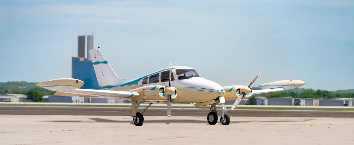 A Piper Apache twin-engine aircraft on the tarmac.