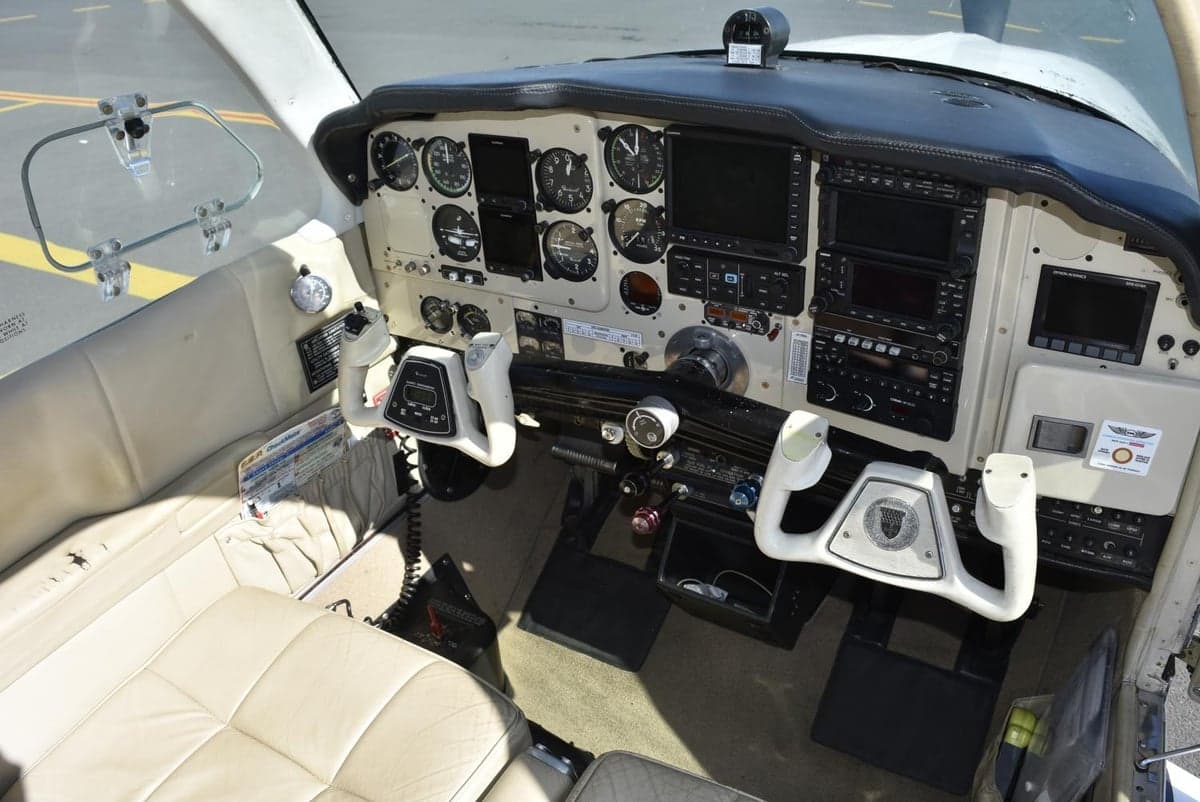 The cockpit of a small aircraft with a mix of analog and digital instruments.