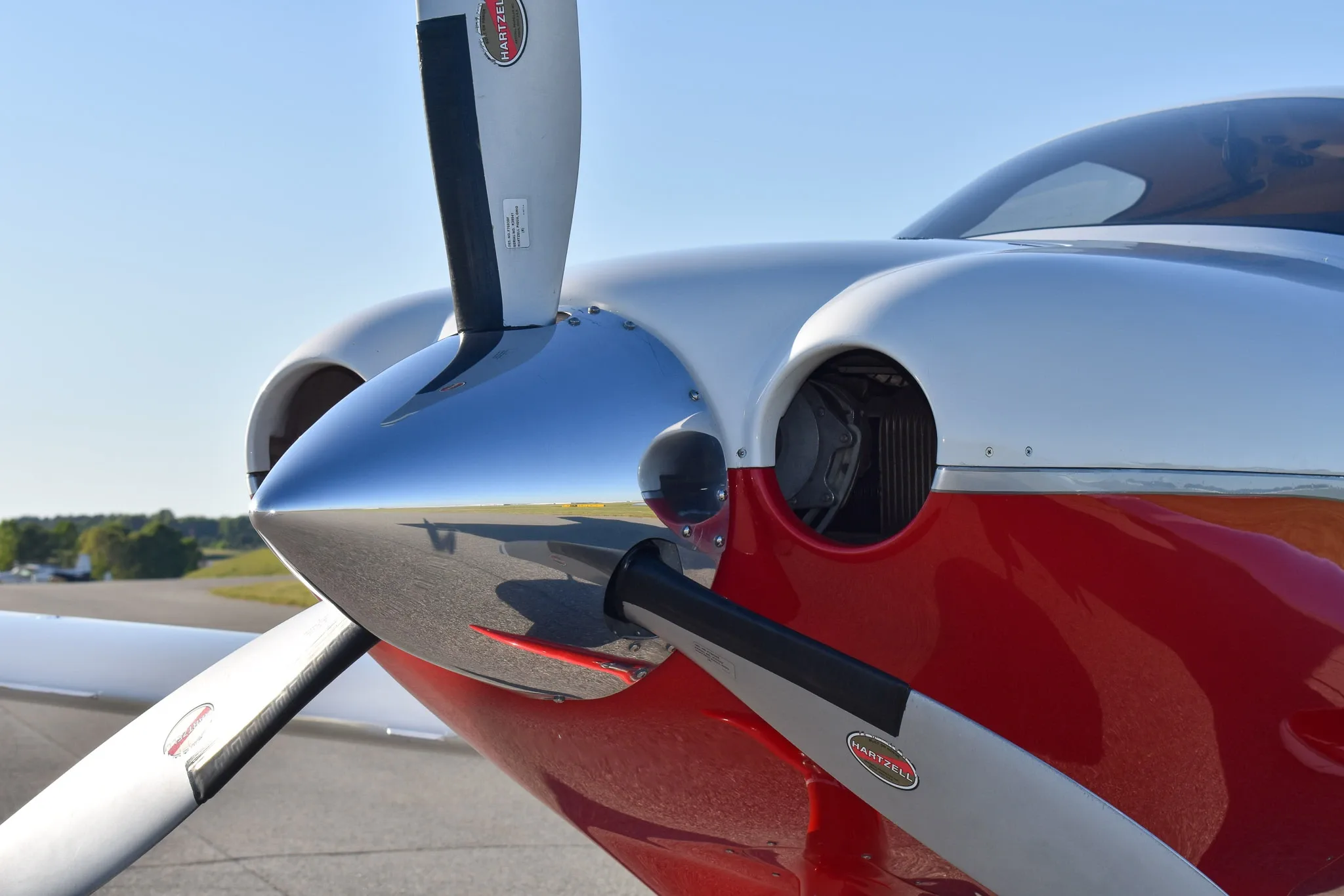 A close-up view of the propeller and polished spinner on the nose of the red and white Cirrus SR22 aircraft.