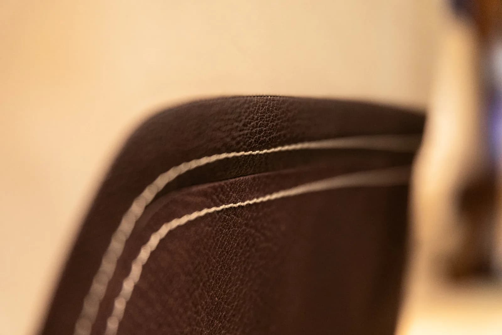 Close-up of a brown leather seat with white stitching.