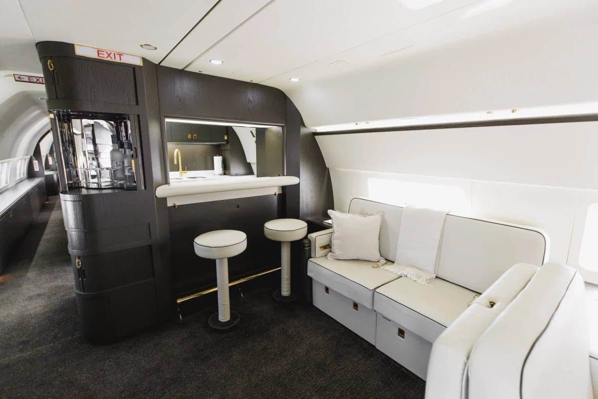 Interior view of the aircraft's bar area with white stools and a white leather sofa.