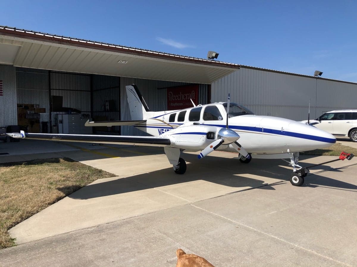 Beechcraft Baron N51FD parked outside a hangar on a sunny day.