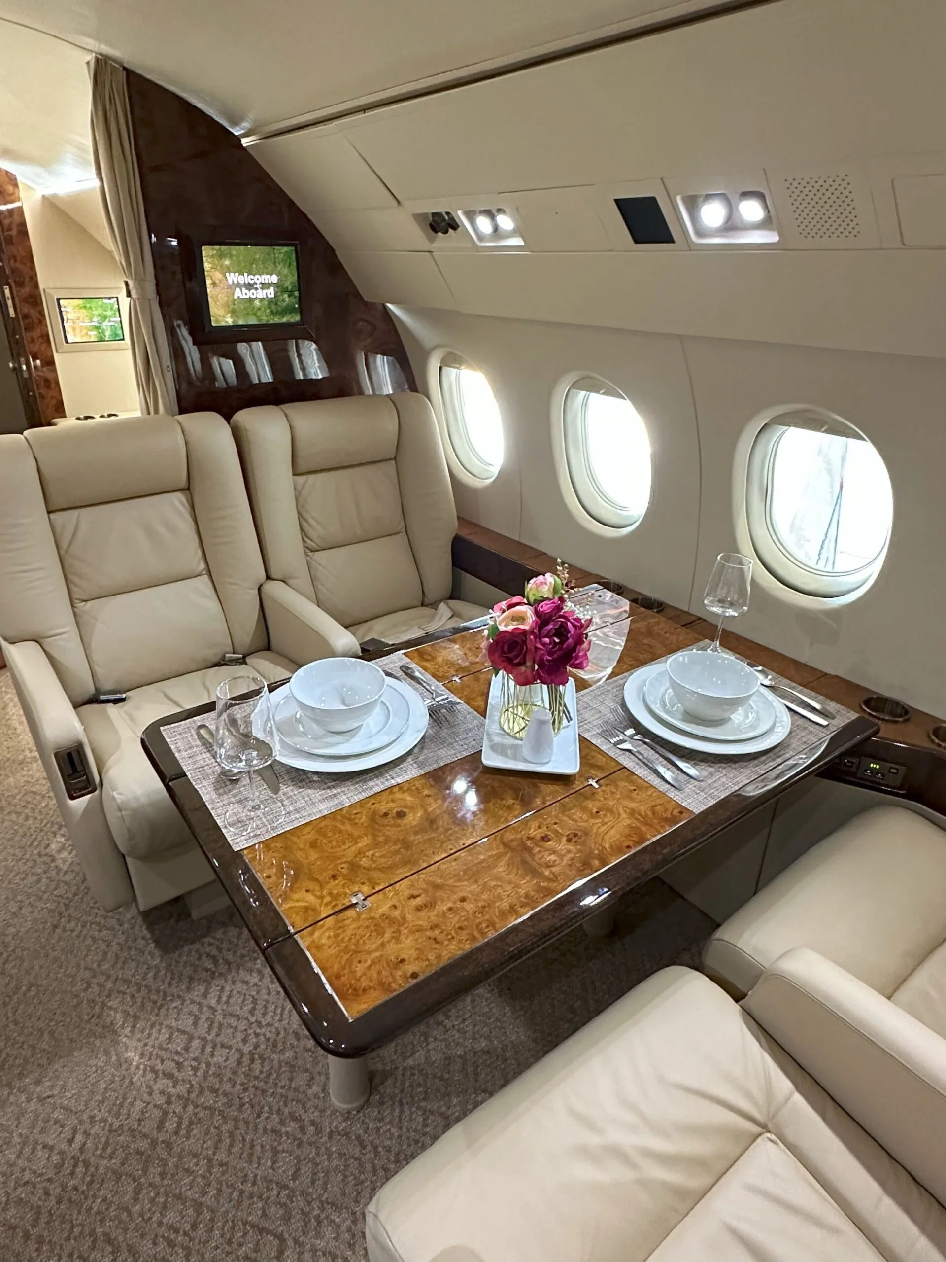 Aircraft cabin with leather seats and a table set for dining.