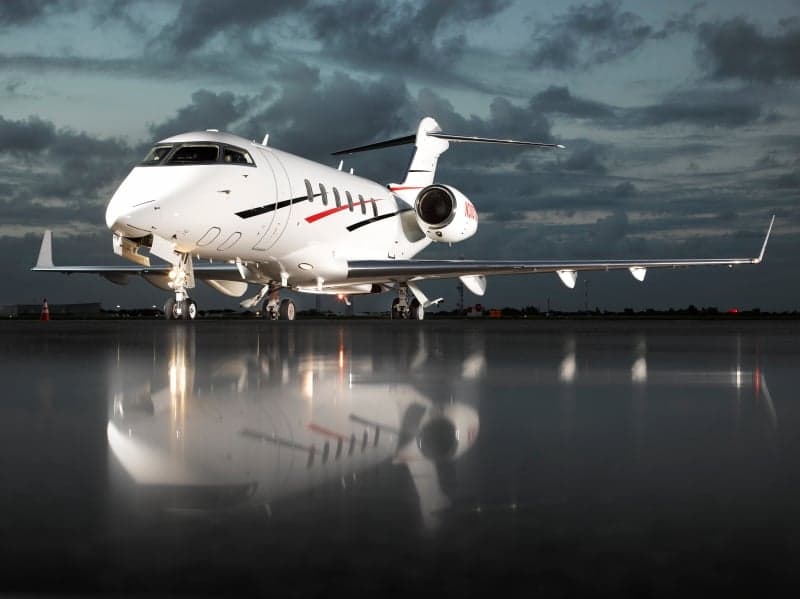 A Bombardier Challenger 350 aircraft with registration N310VZ is parked on the tarmac at dusk.