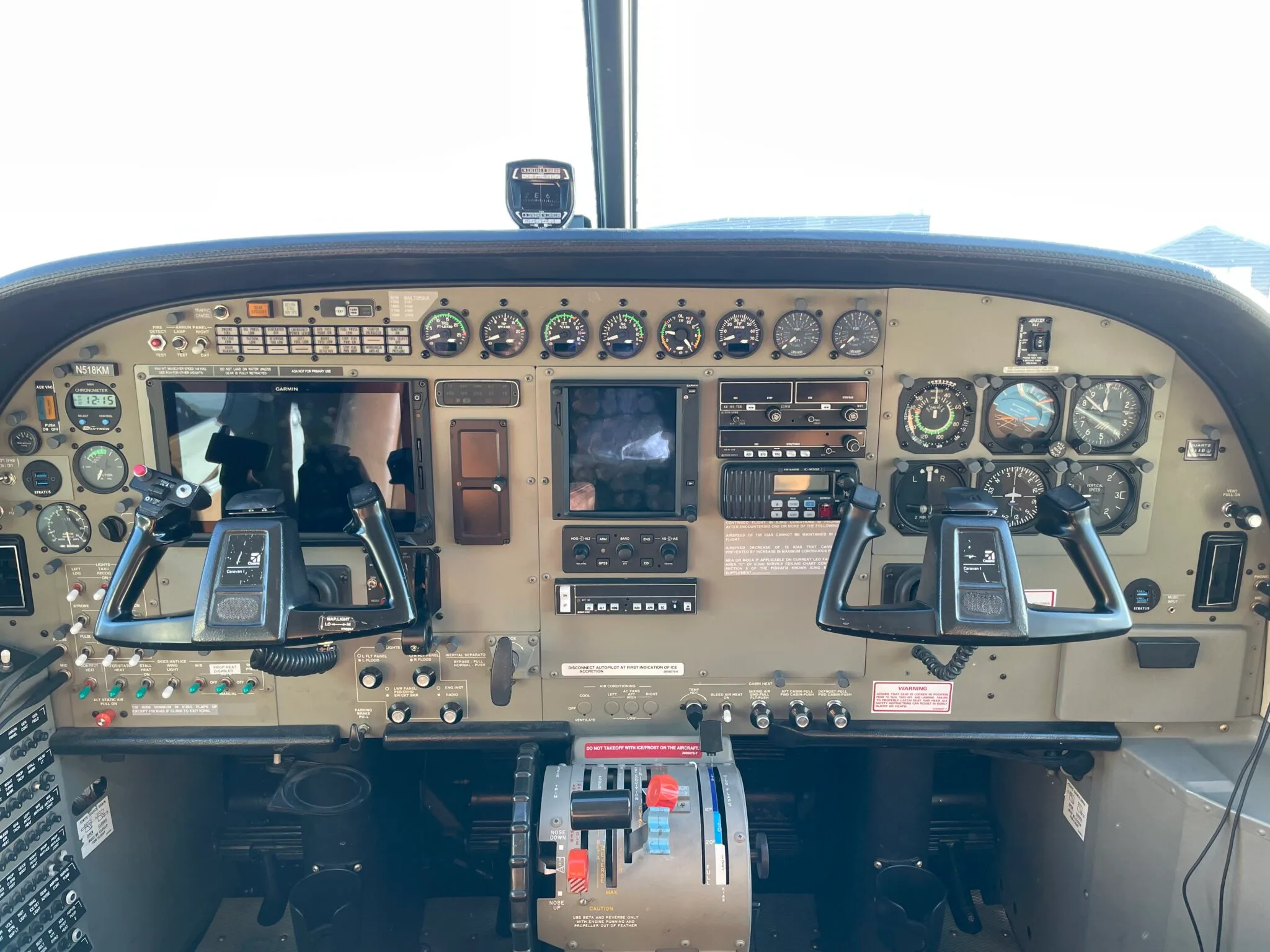 The cockpit instrument panel of an aircraft featuring dual yokes, various analog gauges, and modern digital displays.