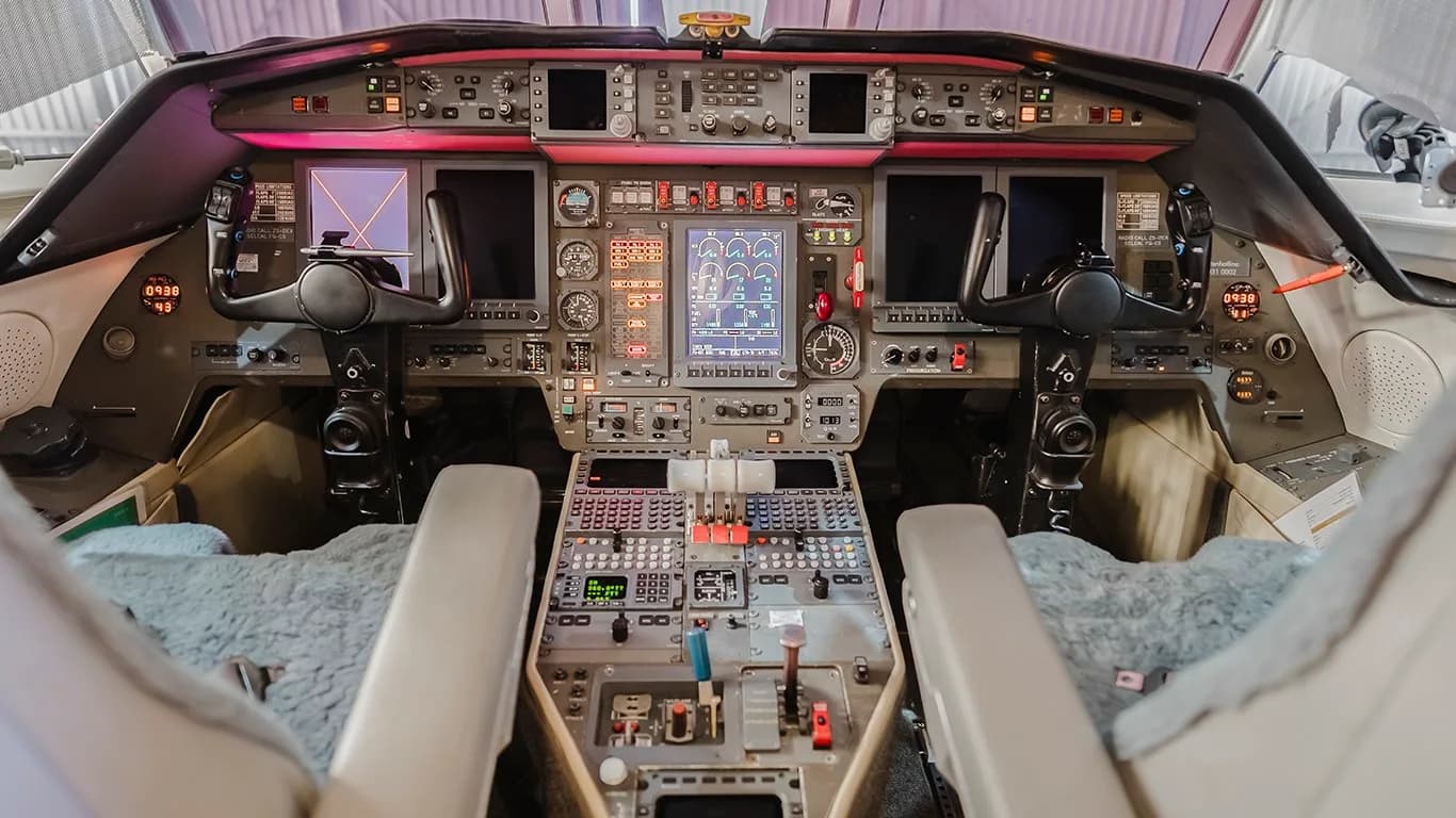 The detailed instrument panel and controls of a modern aircraft cockpit are illuminated.