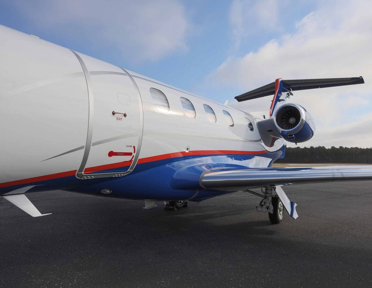 Close-up of the Phenom 300E aircraft's fuselage, showing the door and engine.