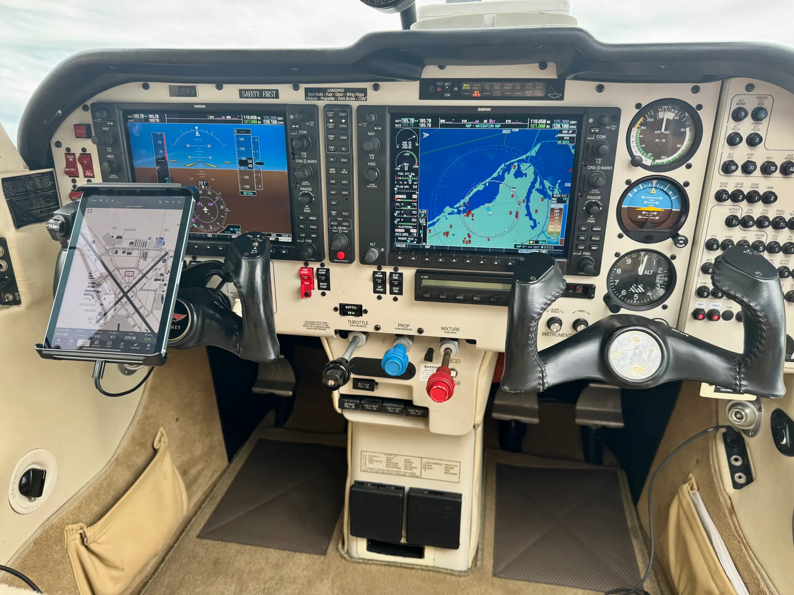 The cockpit of a Mooney Ovation GX, featuring dual Garmin G1000 displays, a tablet on the left yoke, and a beige interior.