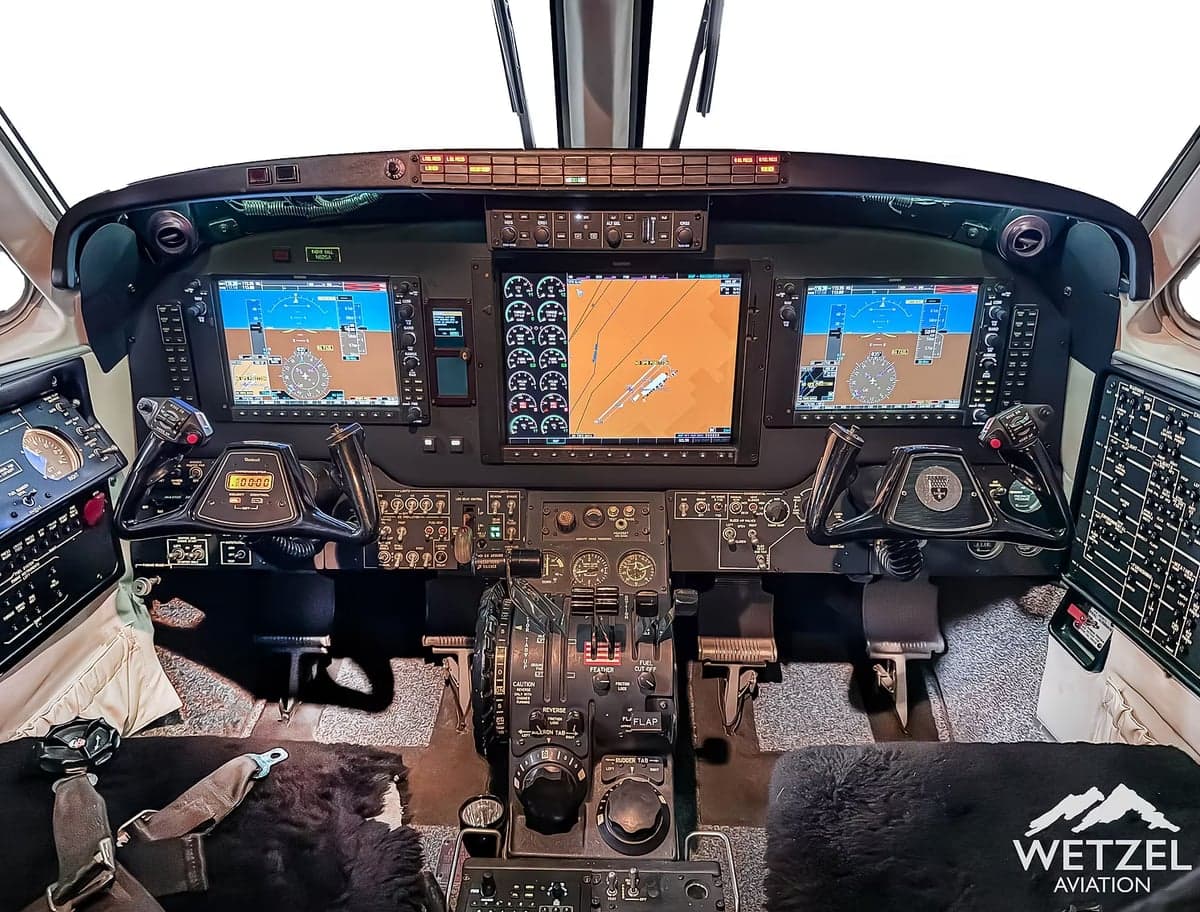 The cockpit of an aircraft featuring a modern glass panel with multiple display screens and control yokes.