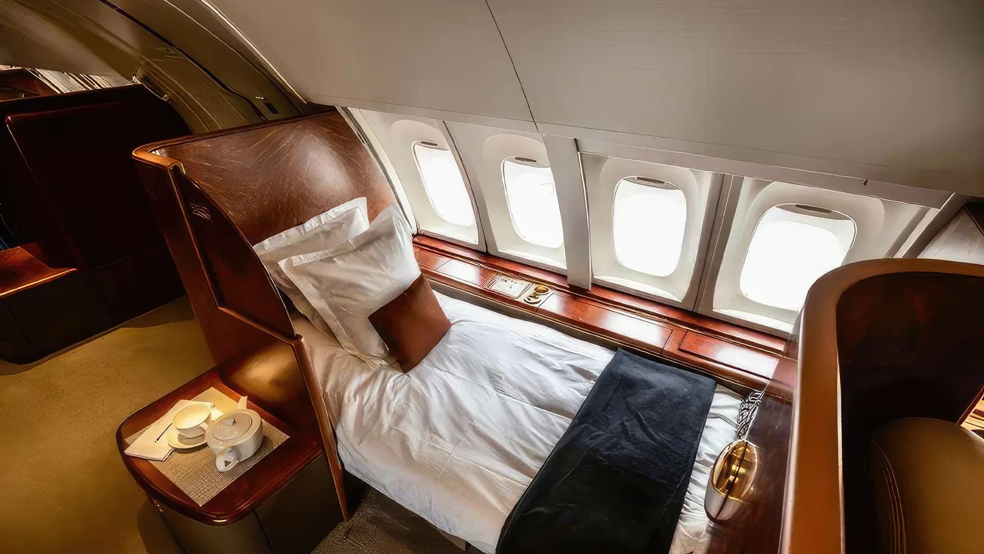 A private jet cabin with a bed and a small table with tea cups.