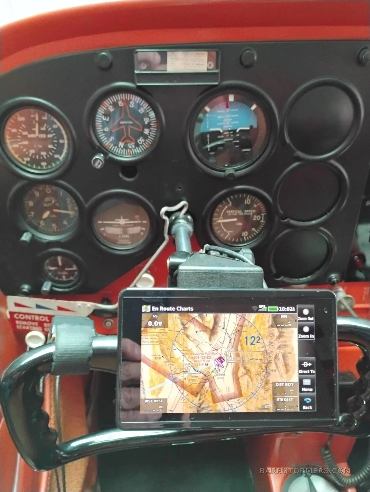 A close-up view of an aircraft instrument panel with a tablet displaying an en route chart mounted on the yoke.