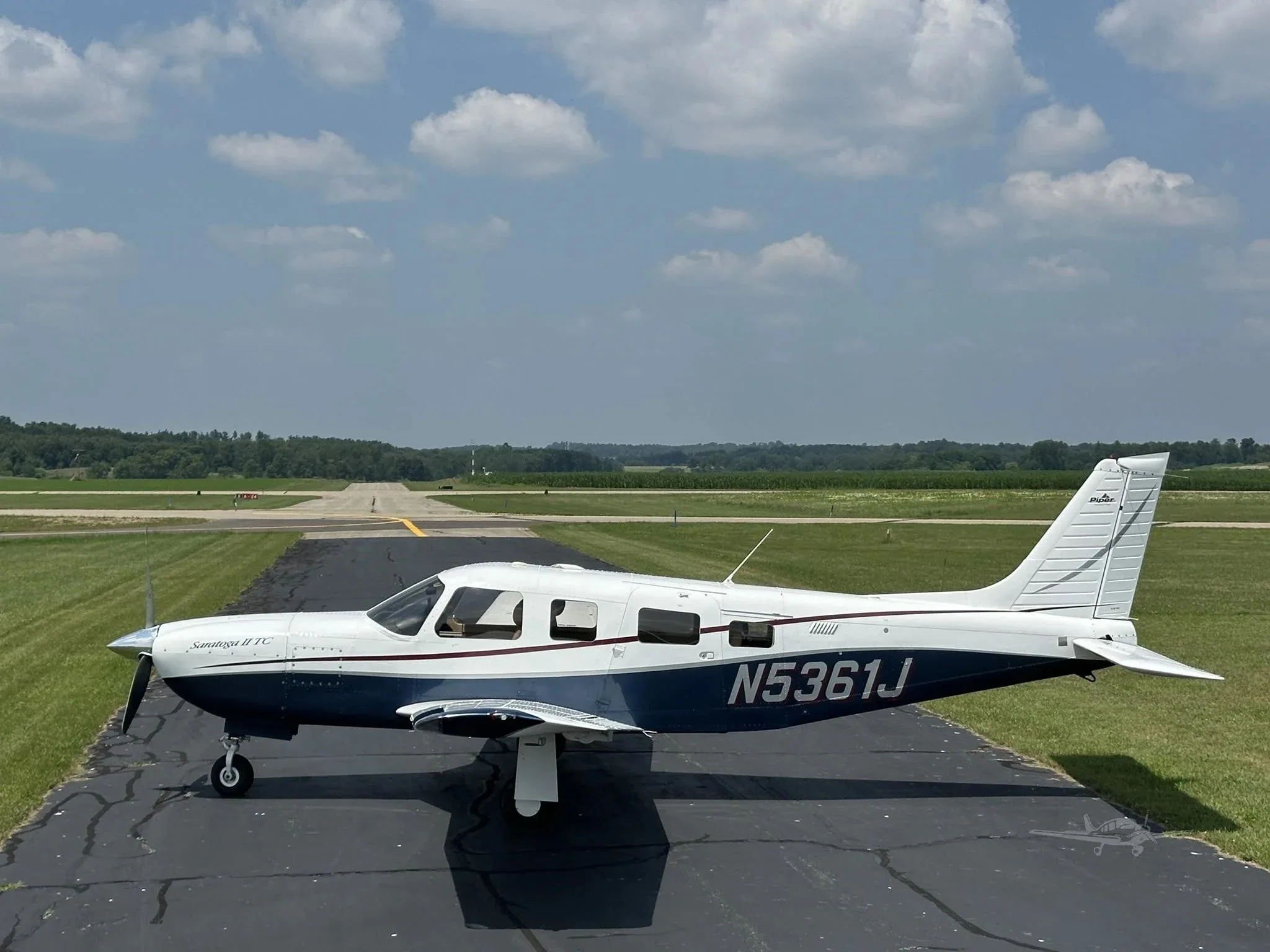 A side profile of the white and blue Piper Saratoga II TC (N5361J) on an airfield.