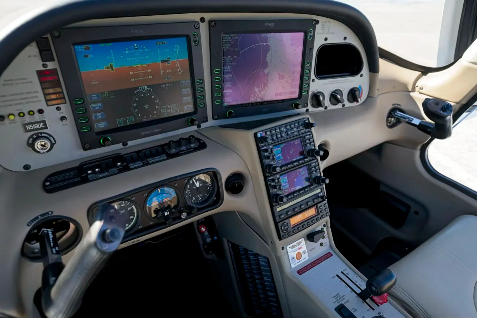 The cockpit of a Cirrus SR22 aircraft, registration N519DE, featuring a modern glass panel display and light tan interior.