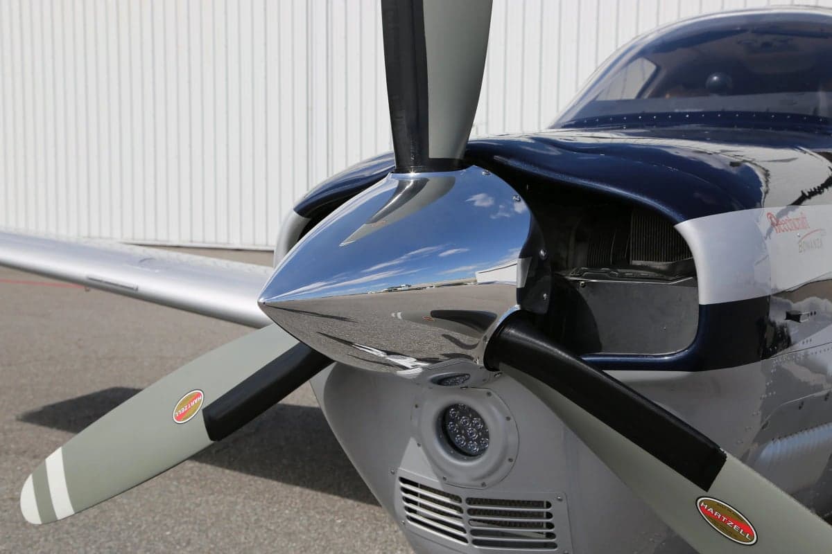 Close-up of the propeller and nose of a Beechcraft Bonanza aircraft.