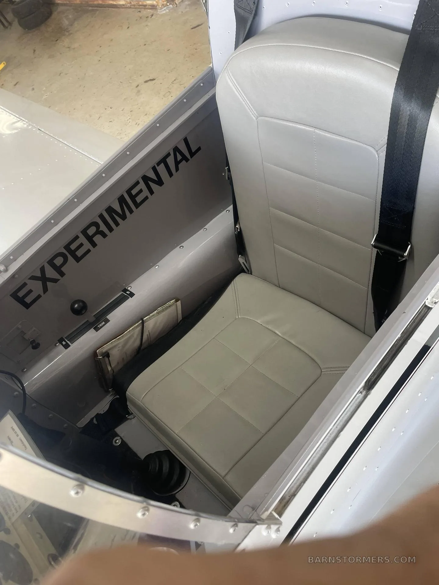 The light gray pilot's seat and "EXPERIMENTAL" text visible on the side panel of an aircraft interior.