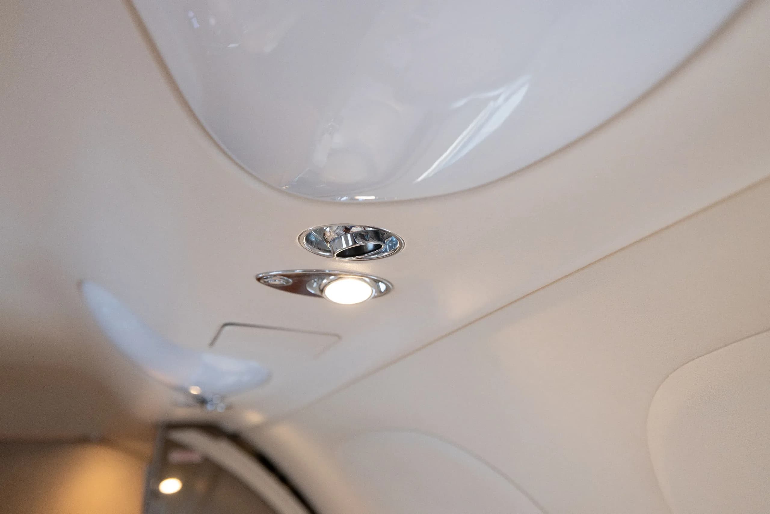 A close-up view of the overhead panel and recessed lighting fixtures in the cabin ceiling of a business jet.