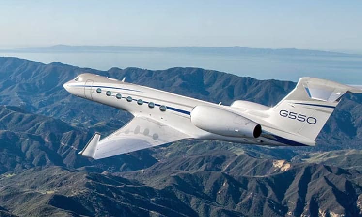 Gulfstream G550 flying over a mountainous landscape.